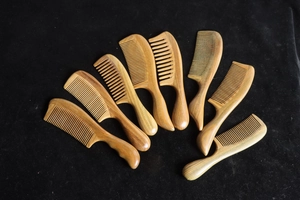 Macro detail of eight premium green sandalwood combs with natural wood grain on black velvet