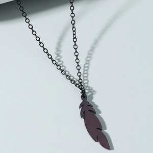 Detail view of the feather-shaped titanium steel pendant with a dark metallic finish