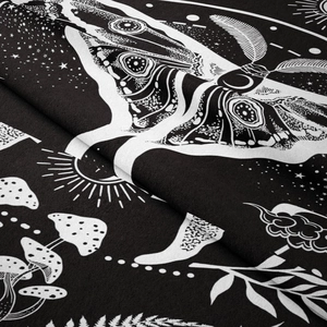 Close-up of black and white bohemian tapestry featuring moth and mushroom patterns