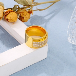 Close-up of wide 18k gold-plated ring with CNC-set cubic zirconia on a white stand