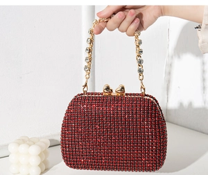 Close-up of red rhinestone evening bag with gold heart clasps and crystal chain handle