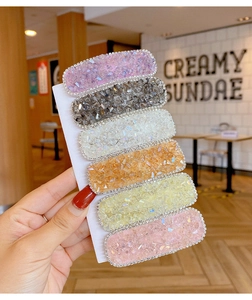 Set of six colorful square hair clips with crystal accents shown in a close-up hand-held view