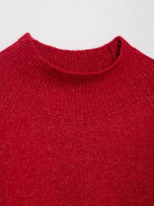 Detail of red knit sweater featuring a ribbed turtleneck collar and premium wool texture