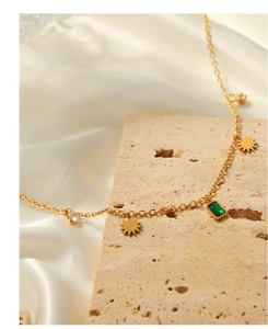 Detail of gold titanium necklace with emerald square pendant and sunburst charms on silk