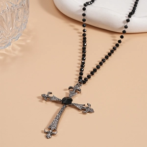 Macro shot of gothic cross necklace with black beads and vintage silver filigree detail
