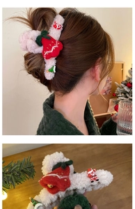 Close-up of a white plush Christmas hair claw clip featuring festive elk and tree charms