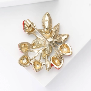 Detail of the golden alloy brooch back with secure pin clasp and red enamel strawberry