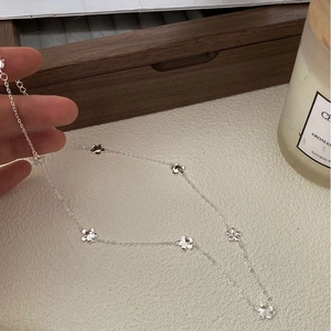 Close-up of 925 sterling silver necklace with delicate daisy flower charms held by hand