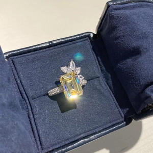 Macro detail of emerald-cut yellow zircon ring with side stones in a blue velvet box