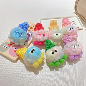 Bunte Plüsch-Oktopus-Schlüsselanhänger mit Strickmützen auf weißem Holzhintergrund
