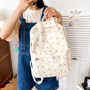 Close-up of cream canvas backpack featuring pink floral rose patterns and front pocket