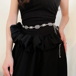 Detail of silver oval vintage metal waist chain styled on a black slim dress