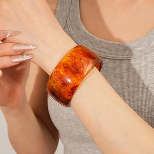 Detailed view of wide amber resin bangle showing natural swirled patterns and glossy finish