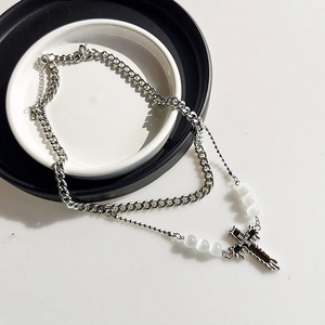 Double-layered silver Cuban chain with white beads and black cross pendant on white plates