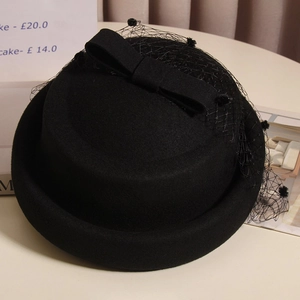 Detailed close-up of a black wool beret featuring a polka dot mesh veil and bow accent