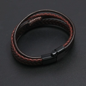 Close-up of multilayer braided leather bracelet with black magnetic clasp on textured surface