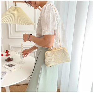 Elegant beige embroidered cheongsam handbag with gold chain strap shown on a female model