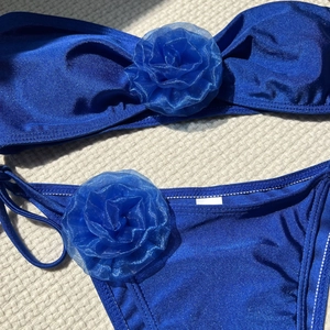 Close-up of royal blue bikini with 3D organza floral accents and shimmering fabric