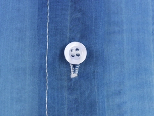 Macro shot of white four-hole button and reinforced stitching on blue organza shirt