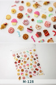 Macro detail of 3D dessert nail stickers featuring donuts and cupcakes on white background