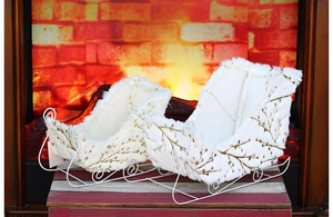 Detailed view of white faux fur Christmas sled decorations with golden leaf patterns