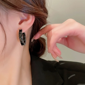 Gros plan de boucles d'oreilles en C ornées de zircons noirs rectangulaires et finition noire