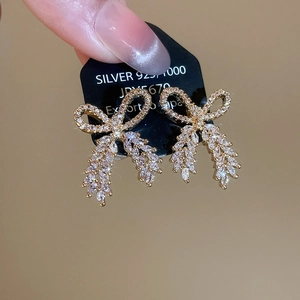 Detailed view of S925 silver golden bowknot and wheat tassel earrings with sparkling zircons