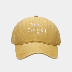 Close-up of mustard yellow washed canvas baseball cap with embroidered white text