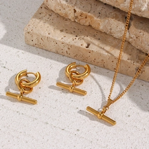 Polished gold T-bar jewelry set featuring a bar and circle pendant on a stone background
