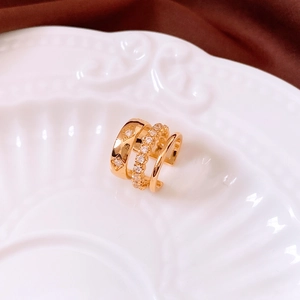 Detailaufnahme einer 18K vergoldeten dreischichtigen Ohrmanschette mit Diamantakzenten