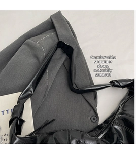 Close-up of black crossbody bag with decorative knotted strap and silver zipper details