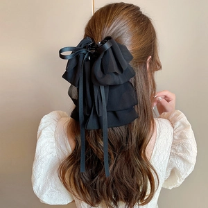 Detail of a large black layered chiffon bow hair claw clip with long ribbons on wavy hair