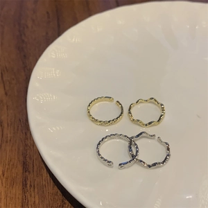 Detailed view of gold and silver plated wave rings and braided twist rings on a ceramic plate