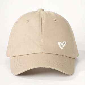 Détail de casquette beige en coton avec cœur blanc dessiné et visière courbée