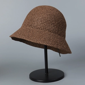 Detail of dark brown hand-crocheted straw bucket hat with textured weave on display stand