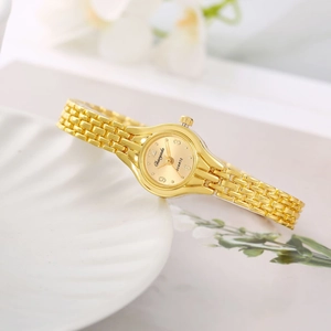 Detail of elegant gold women's quartz watch with metal bracelet on a decorative shell