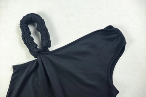 Detail eines schwarzen One-Shoulder-Kleides mit elegantem gerafftem Träger und Stoff