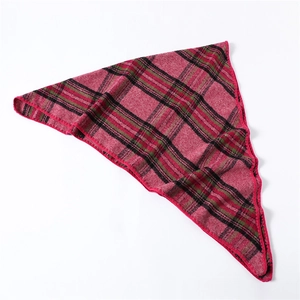 Detail shot of red plaid triangular scarf showing soft texture and tassel edges