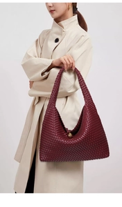 Detail of burgundy woven leather shoulder bag showing intricate texture and golden hardware