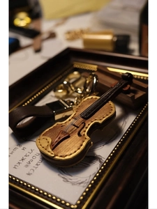 Macro detail of violin keychain with leather texture and gold edges in artistic frame