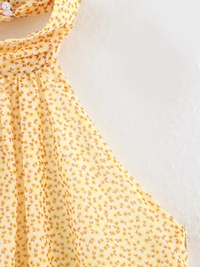 Dettaglio di abito floreale con allacciatura al collo, bottone e trama in chiffon leggero