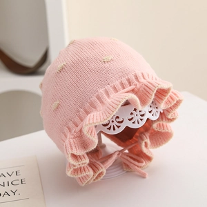 Dettaglio cappello neonato in maglia rosa con volant e interno in pizzo