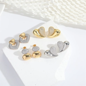 Romantic long heart-shaped gold and silver earrings with pavé zircon stones on white display