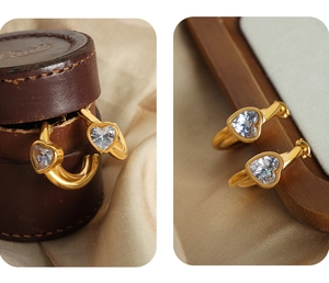 Dettaglio di orecchini a cuore con zircone appesi a un portagioie in pelle vintage