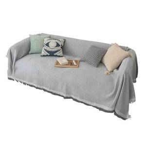 Gray striped textured sofa throw blanket with tassel fringe edge on a two-seater sofa