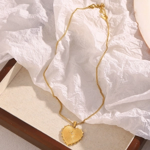 Detail of 18K gold-plated heart necklace with radiant texture and center crystal