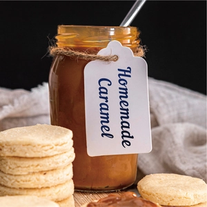 Close-up of Homemade Caramel jar and golden cookies against a dark textured background