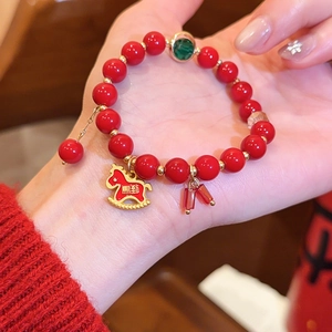 Detailansicht eines roten Achat-Perlenarmbands mit goldenem Schaukelpferd-Anhänger.