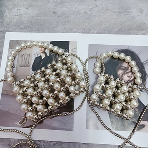 Detail of handcrafted silver and pearl beaded mini handbag with chain on magazine
