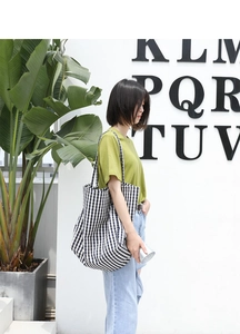 Detail shot of a large black and white checkered canvas tote bag worn on shoulder